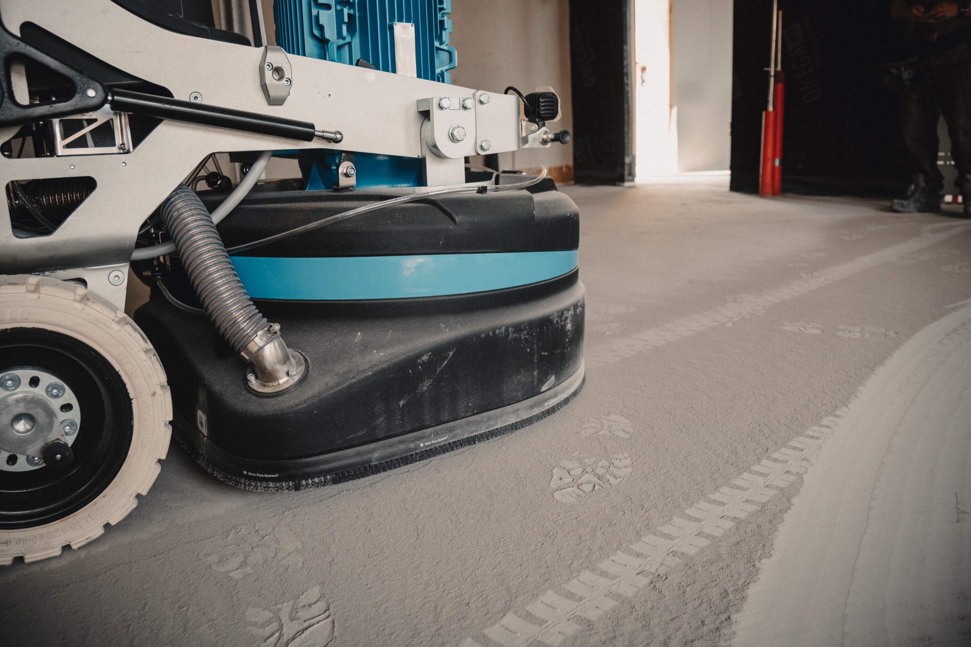 Schleifmaschine auf unbearbeitetem Rohbeton mit Fußspuren