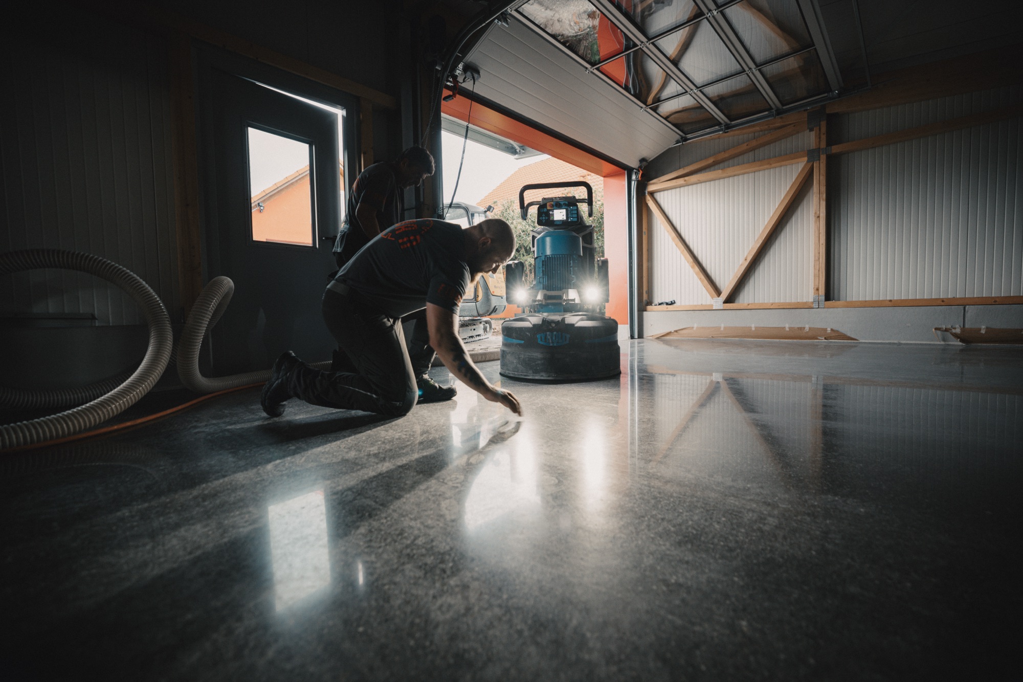 Monteur kniet und prüft den geschliffenen Boden