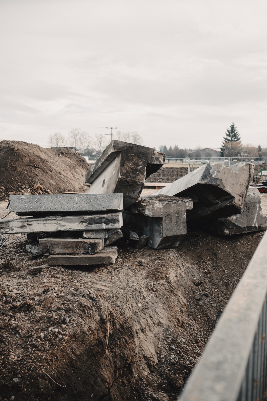 Abgebrochene Stahlbetonteile der Brücke aufgestapelt neben der Baustelle
