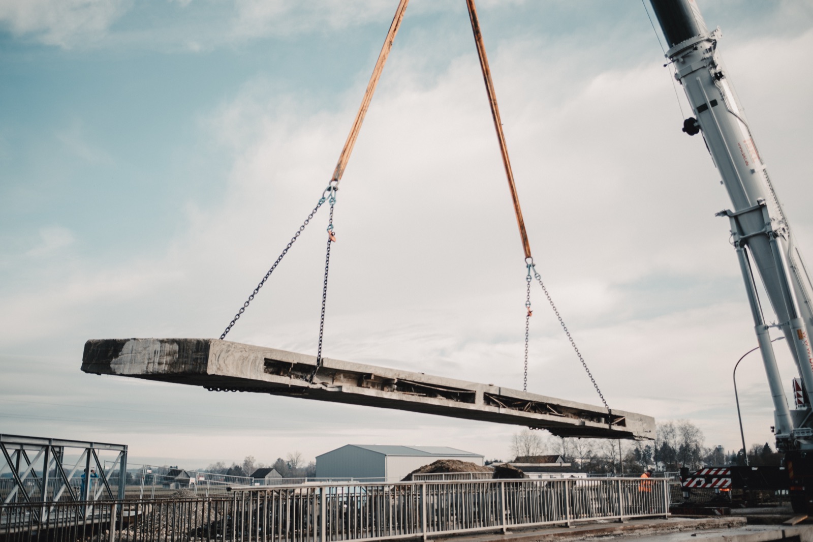 Schwerlastkran hebt ein mehrtonniges Brückensegment aus Stahlbeton in die Luft