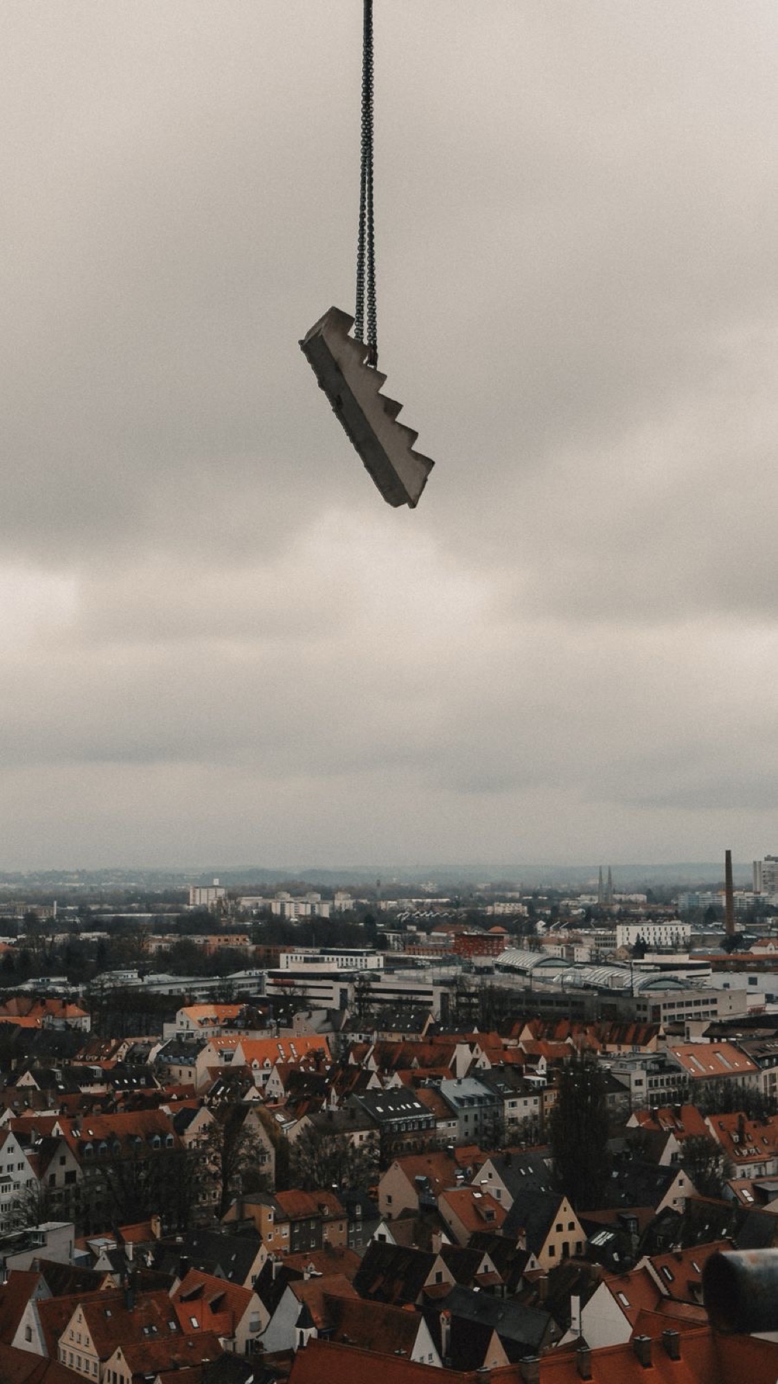 Herausgesägtes Treppensegment hängt am Kran über den Dächern von Augsburg