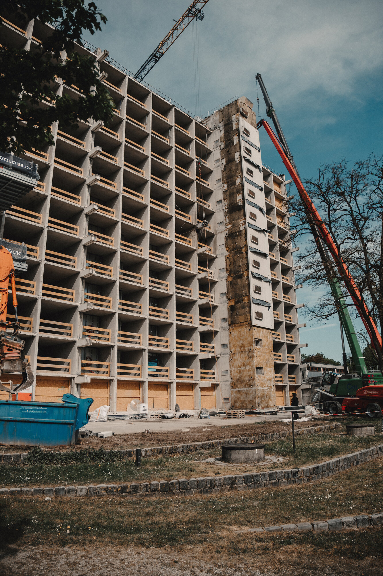Hochhaus der Studentenstadt München mit freigelegten Kragarmen, roter Mobilkran im Einsatz