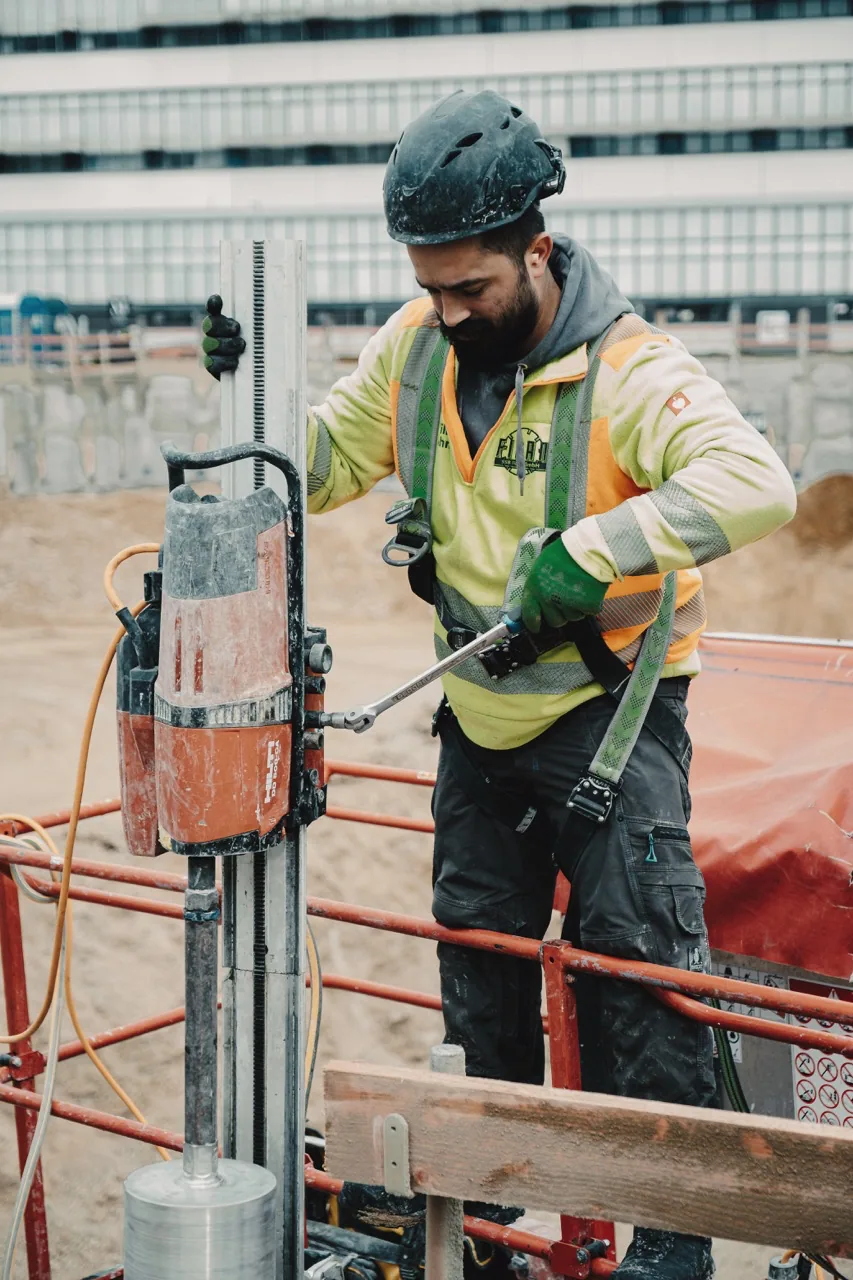 Fidan-Monteur in Warnweste an der Kernbohrmaschine auf der Baustelle